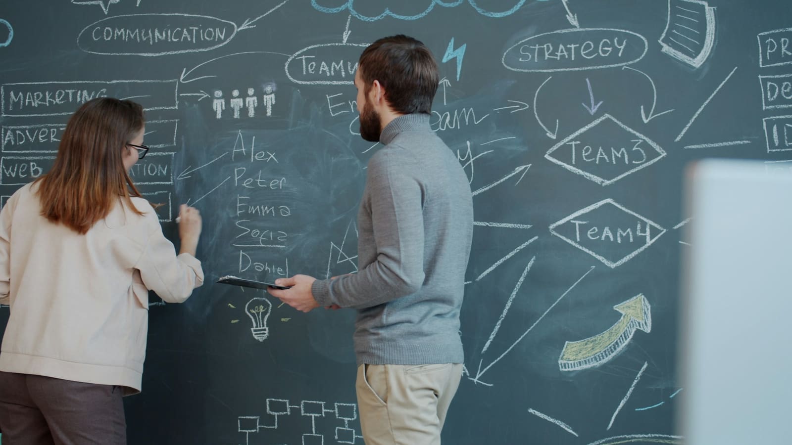 Two people planning together beside a board of diagrams