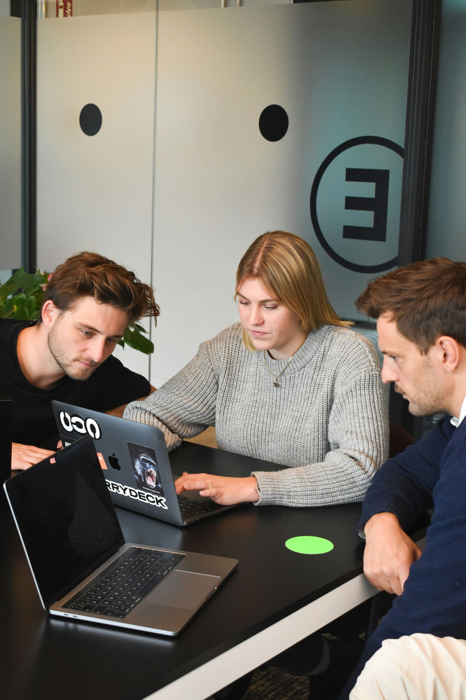 Three people collaborating around a laptop at a table